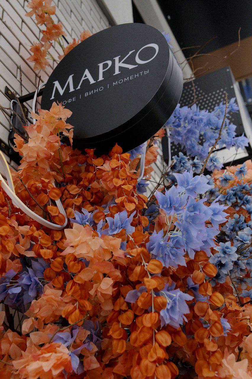 Вход в МАРКО: круглая вывеска и весенние цветы